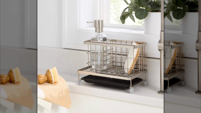 Metal sink caddy holding sponge and dish soap on white countertop.