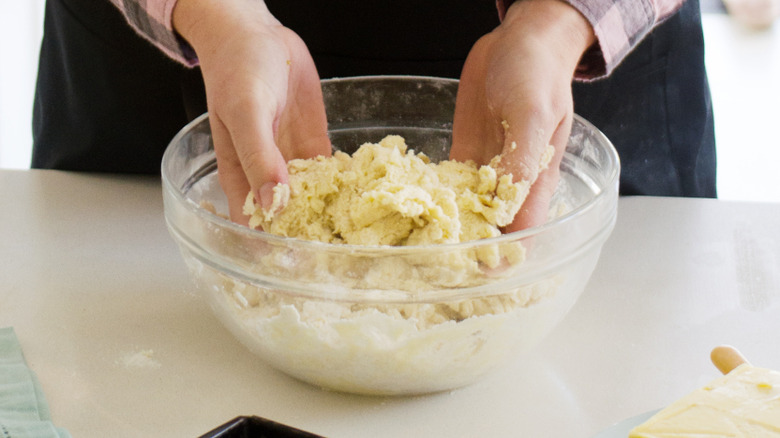 Person stirring scone batter in hands