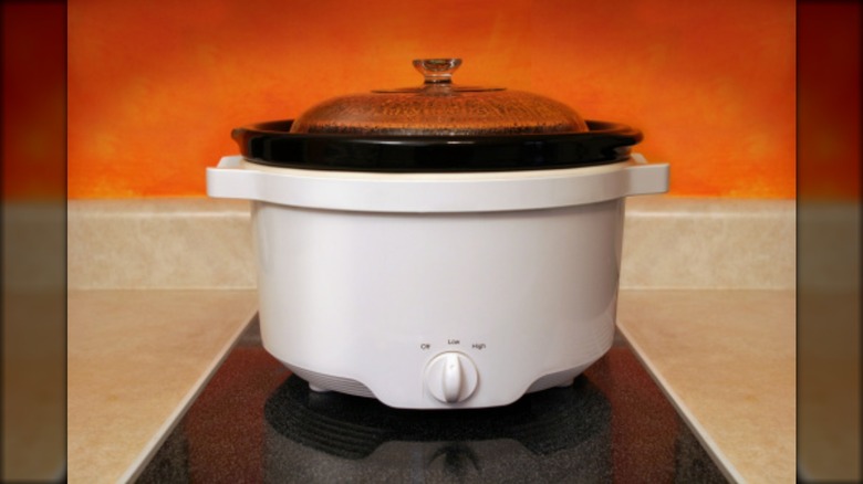 A slow cooker on an orange background