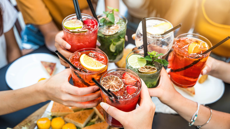 A group of people toast with glasses of colorful beverages