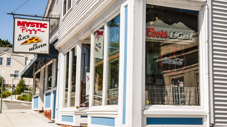 The exterior of Mystic Pizza restaurant with a hanging sign