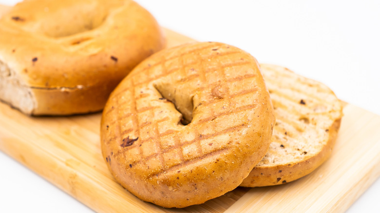 two sliced whole wheat bagels on cutting board
