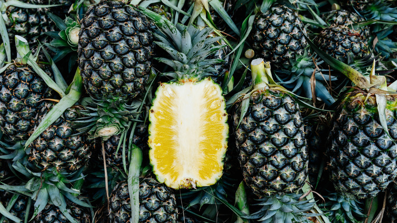 a half of a pineapple surrounded by whole pineapples