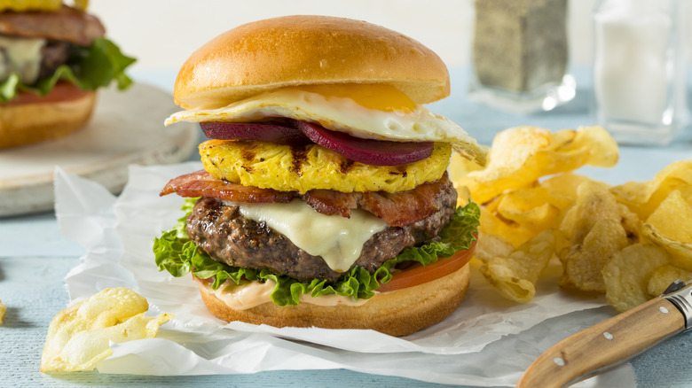 An Aussie burger with egg, pineapple, bacon, cheese, and beet root