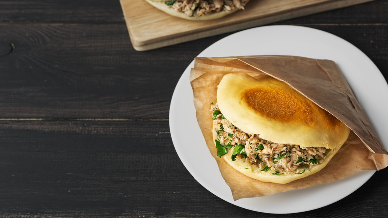 A rou jia mo wrapped in paper on a plate