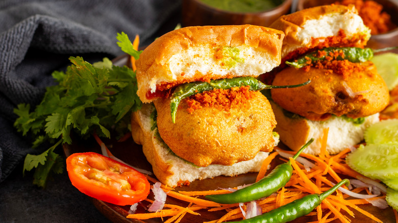 Two vada pavs on a plate with garnishes
