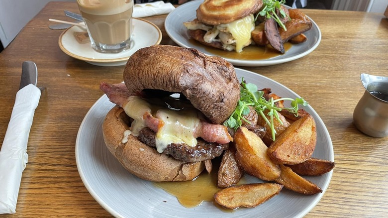 A Yorkshire pudding burger on a plate with potato wedges