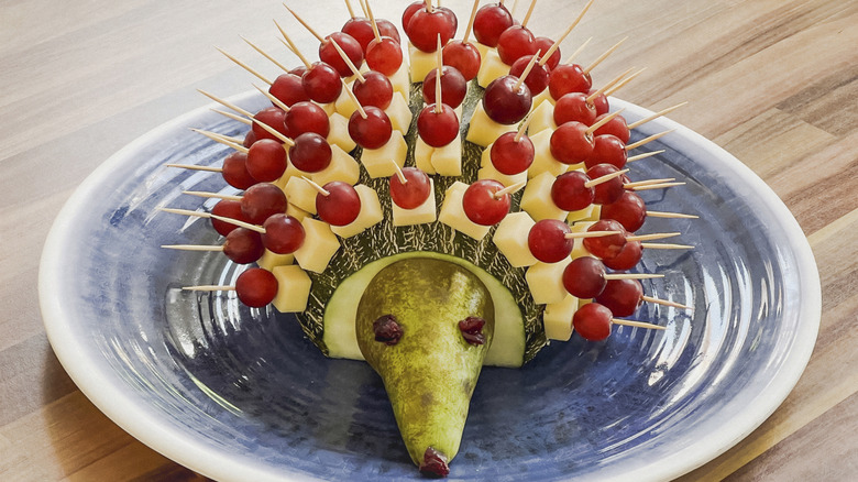 A melon with cheese and grape toothpicks sticking out like a hedgehog