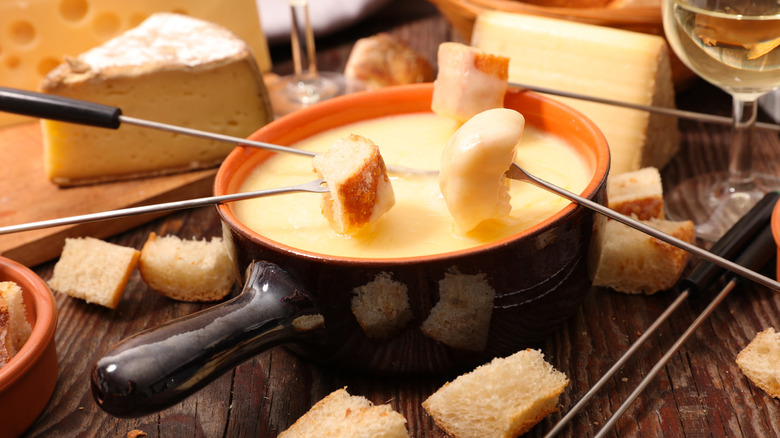 A pot of cheese fondue with skewers of bread