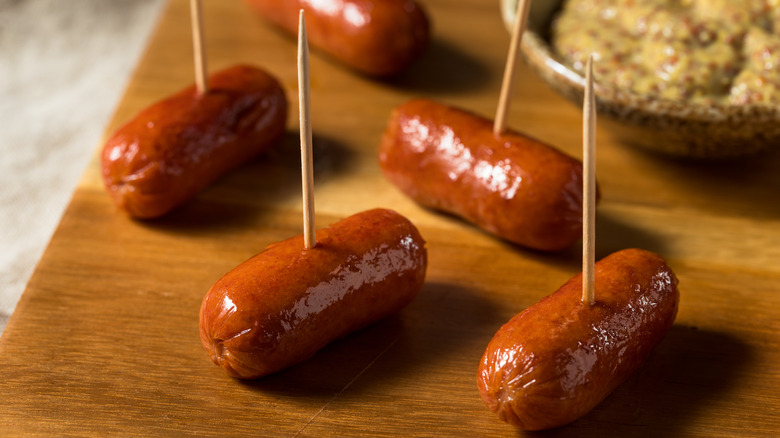 Cocktail weiners with toothpicks on a wooden cutting board