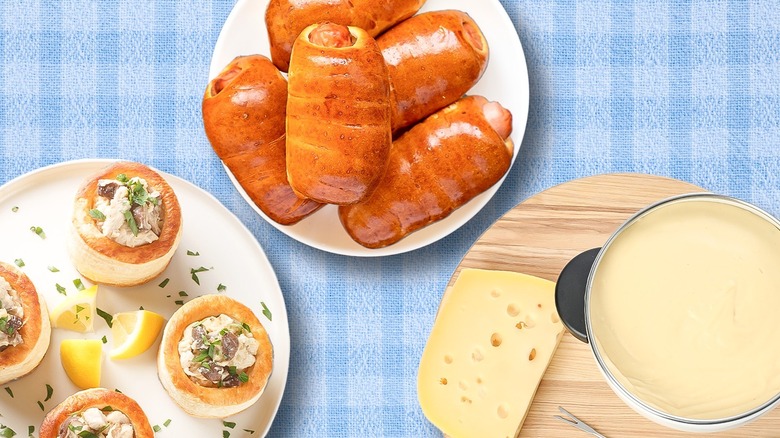 A spread of 1970s appetizers including vol au vents, pigs in blankets, and cheese fondue