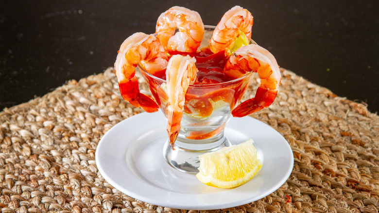 A prawn cocktail with cocktail sauce and a lemon
