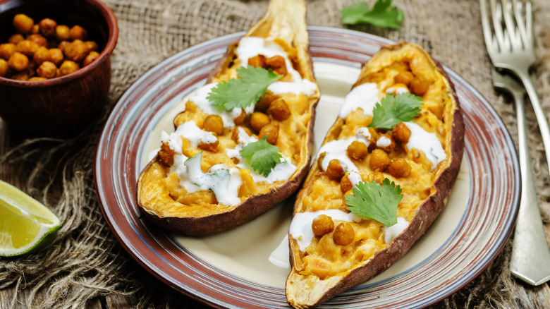 a stuffed sweet potato with chickpeas and cream on colorful plate