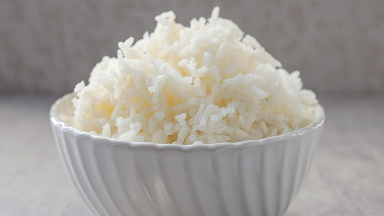 cooked white rice in white bowl on rustic background