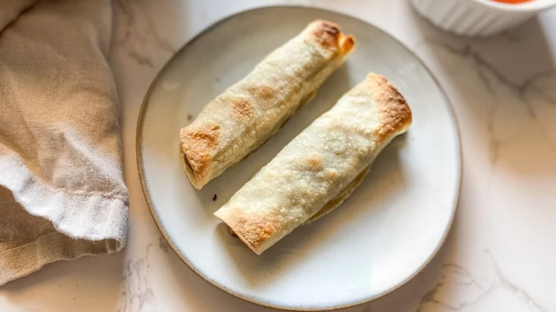 Two baked taquitos served on a white plate