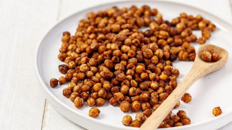 Roasted chickpeas on a white plate, with a wooden spoon at the side