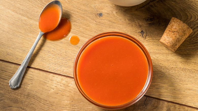 A bowl and spoon of Buffalo sauce