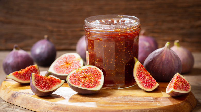 A jar of fig jam next to fresh figs
