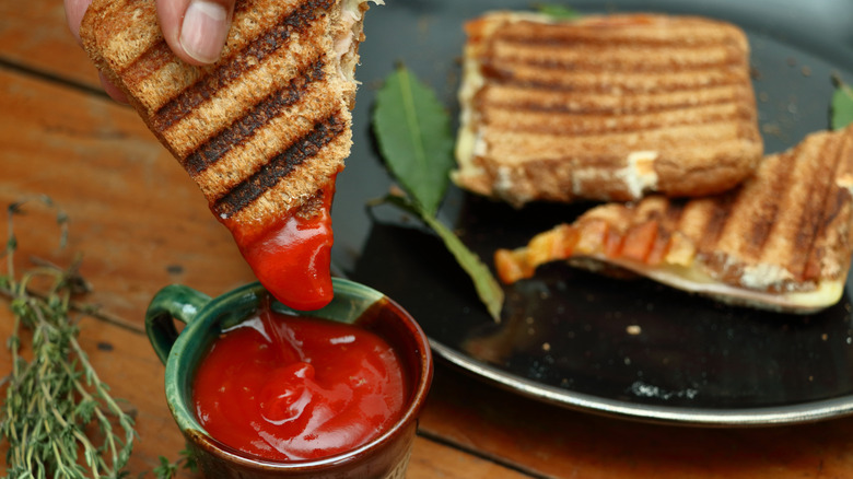 A grilled cheese sandwich is dipped into ketchup