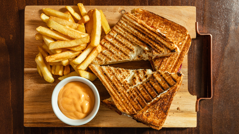 A grilled cheese with French fries and spicy mayo