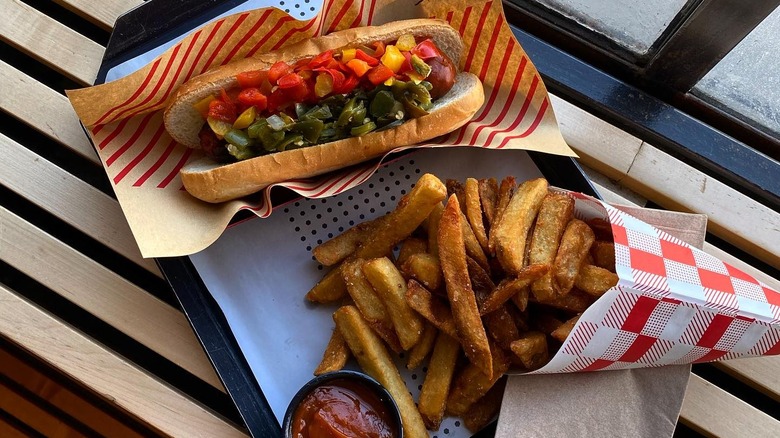 A sausage in a bun with condiments and fries at Würstkuche