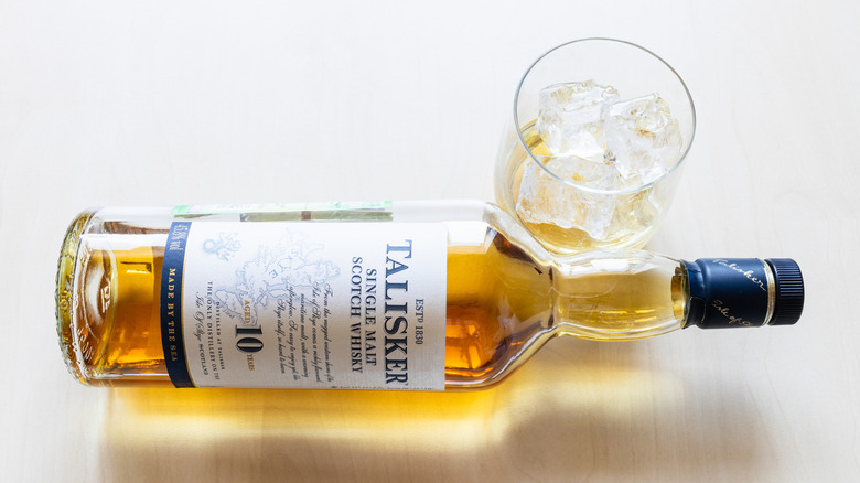 A bottle of Talisker 10 Year lying on its side with a glass
