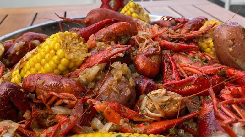 Seafood boil with crawfish, potatoes, and corn on table outside