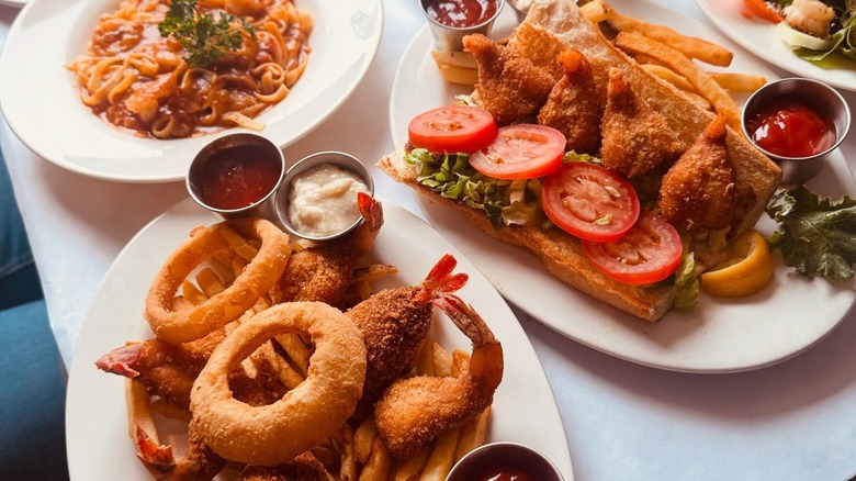 Assorted plates including fried shrimp, onion rings, and pasta
