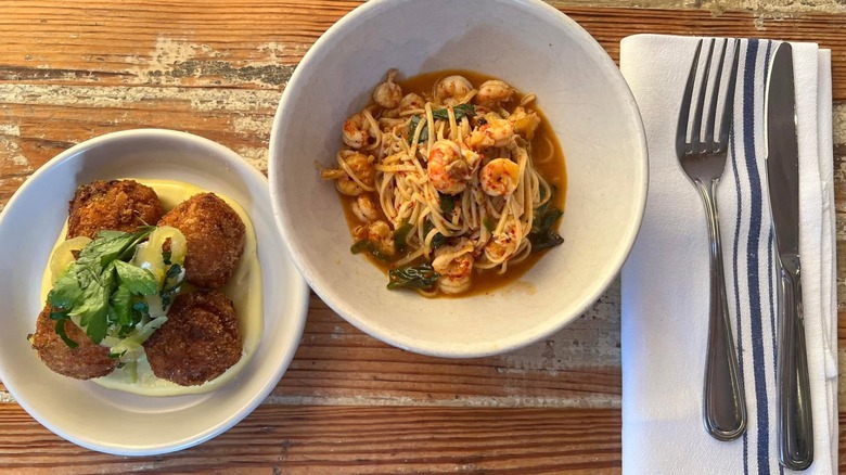 Crawfish capellini and crawfish croquettes on wooden table with silverware