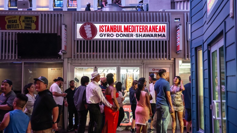 people queue up at an outlet of various food, with a sign for mediterranean food