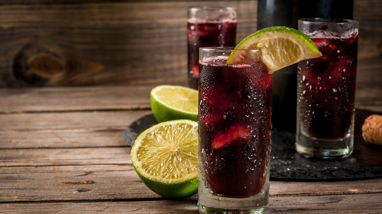 Three kalimotxo drinks with lime in glasses with heavy condensation
