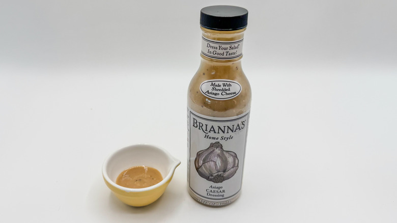 Bottle of Caesar dressing with sample cup of dressing