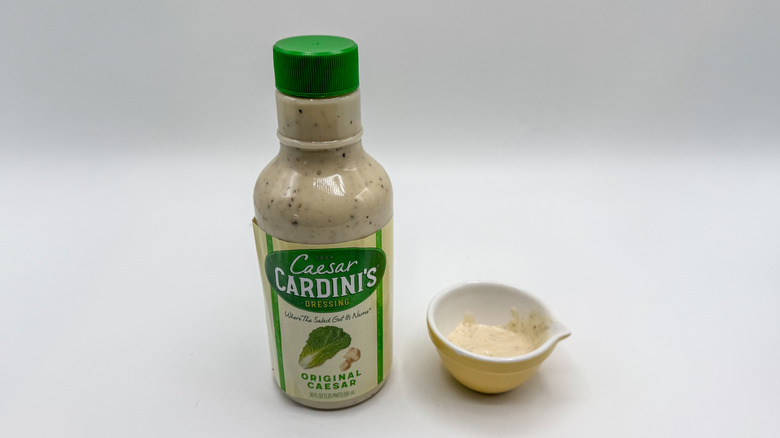 Bottle of Caesar dressing with sample cup of dressing