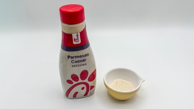 Bottle of Caesar dressing with sample cup of dressing