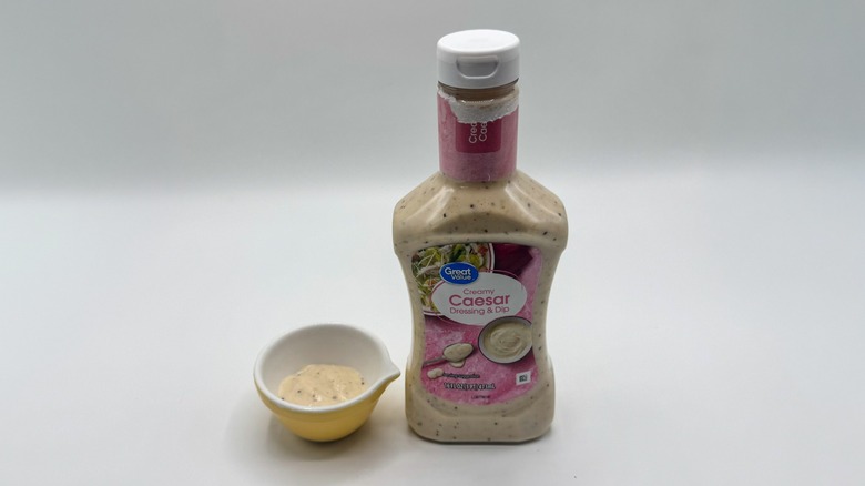 Bottle of Caesar dressing with sample cup of dressing