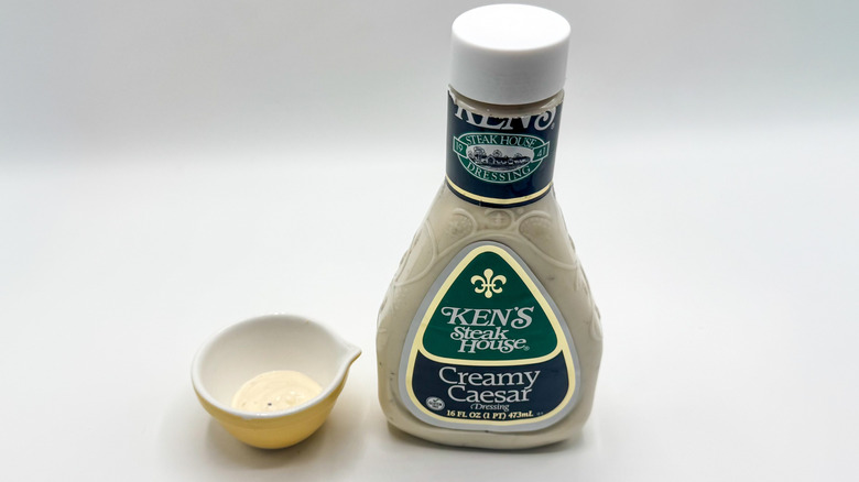 Bottle of Caesar dressing with sample cup of dressing