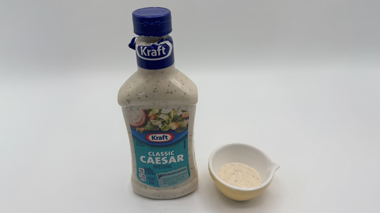 Bottle of Caesar dressing with sample cup of dressing