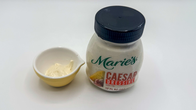 Bottle of Caesar dressing with sample cup of dressing