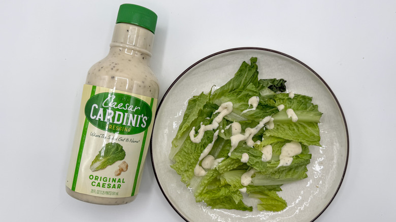 Bottle of Caesar dressing and a dressed plate of lettuce