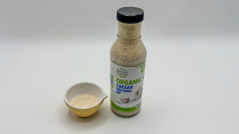 Bottle of Caesar dressing with sample cup of dressing