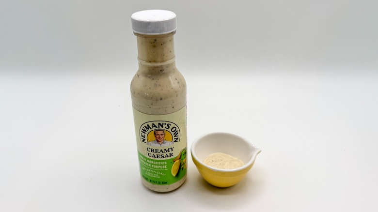 Bottle of Caesar dressing with sample cup of dressing