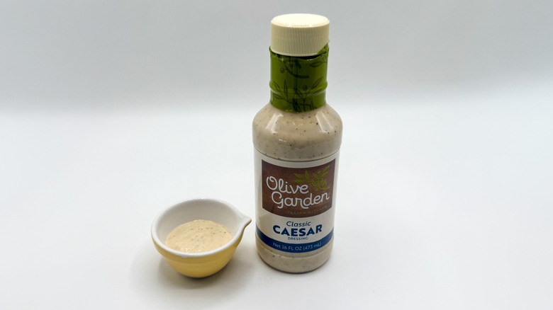 Bottle of Caesar dressing with sample cup of dressing