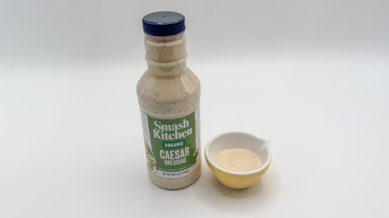 Bottle of Caesar dressing with sample cup of dressing