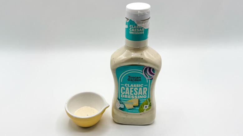Bottle of Caesar dressing with sample cup of dressing