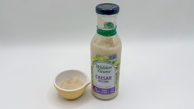 Bottle of Caesar dressing with sample cup of dressing
