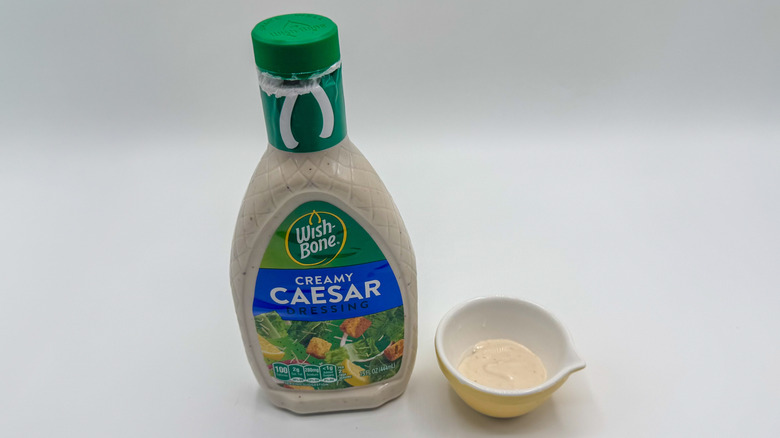 Bottle of Caesar dressing with sample cup of dressing
