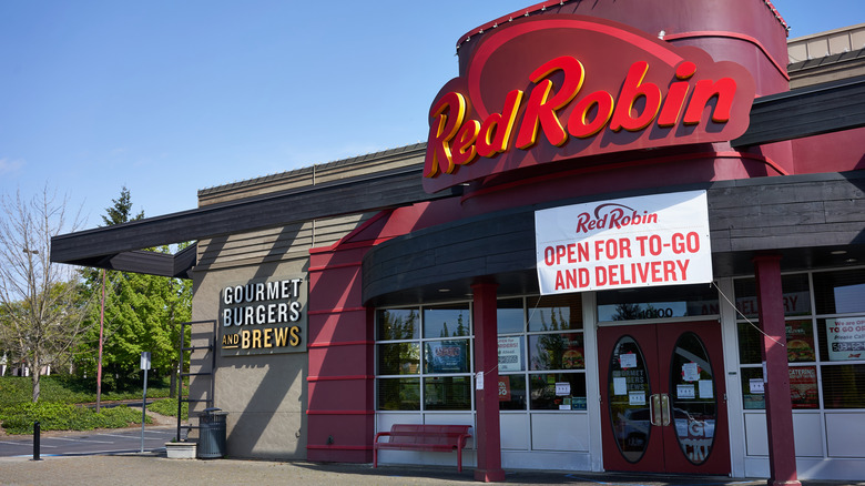 The exterior of a Red Robin restaurant with blue sky and trees in the background