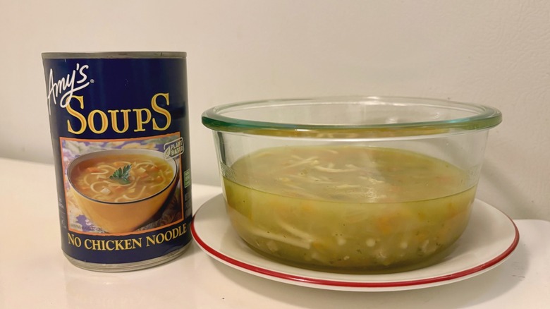 A can of Amy's No Chicken Noodle Soup next to a prepared bowl of soup on a plate