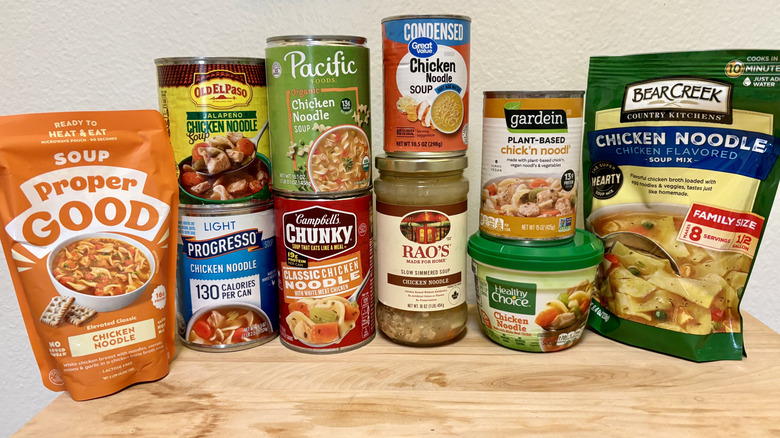 Variety of chicken noodle soup products stacked on top of each other on wooden table