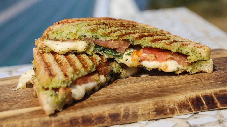 Halved grilled cheese sandwich with basil pesto and tomatoes